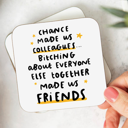 White coaster that reads 'Chance Made Us Colleagues... Bitching About Everyone Else Together Made Us Friends' in a playful font and with with yellow stars.