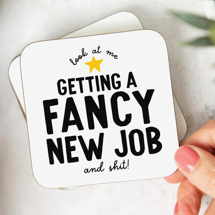 White coaster with a yellow star and bold black text that reads 'look at me getting a fancy  new job and shit'.