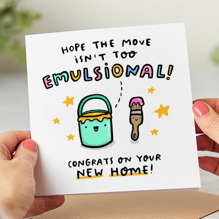 Folded white card that says 'Hope the move isn't too emulsional! congrats on your new home!' With a paint brush and bucket covered in paint