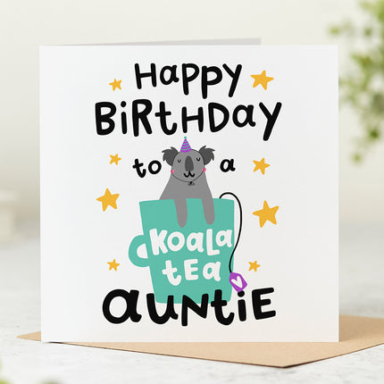 White greeting card that reads 'Happy Birthday To A Koala Tea Auntie' with a playful illustration of a koala sitting in a mug.