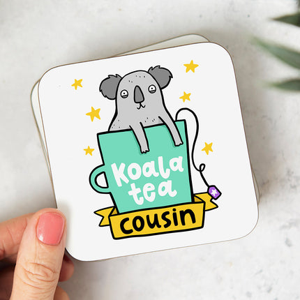 White coaster with a playful illustration of a koala bear sitting in a mug, followed by the text 'Koala Tea Cousin'.