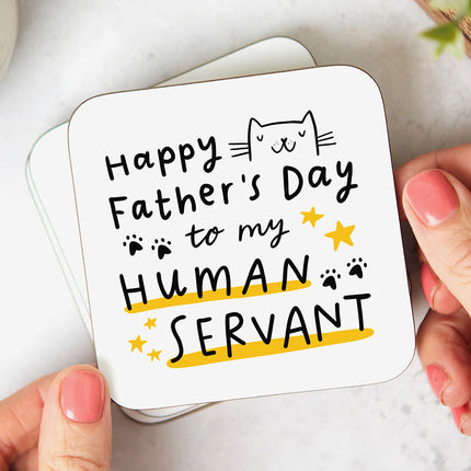 White coaster that reads 'Happy Father's Day To My Human Servant' with a cat cartoon illustration and paws and stars.
