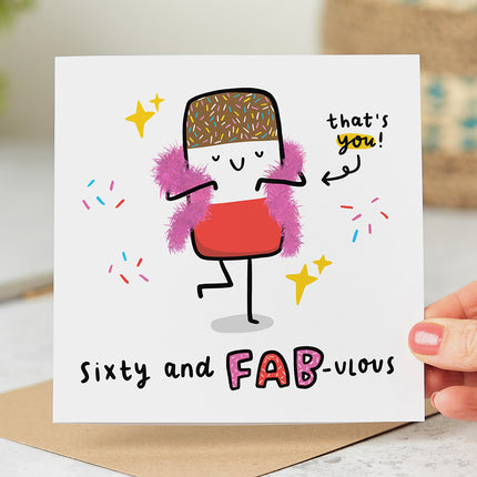 Birthday card with an image of a bright and colourful ice lolly wearing a feather boa. The text on the card reads 'Sixty and Fab-ulous' in bold, playful letters.