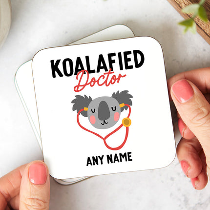 A hardboard coaster with a cute koala illustration and the phrase 'Koalafied Doctor'. The coaster can be personalised with any name.