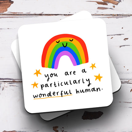A white coaster with a rainbow illustration and the text 'You Are A Particularly Wonderful Human'.